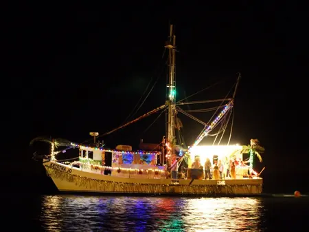 A shrimp boat strung with lights on the water at night during the boat parade